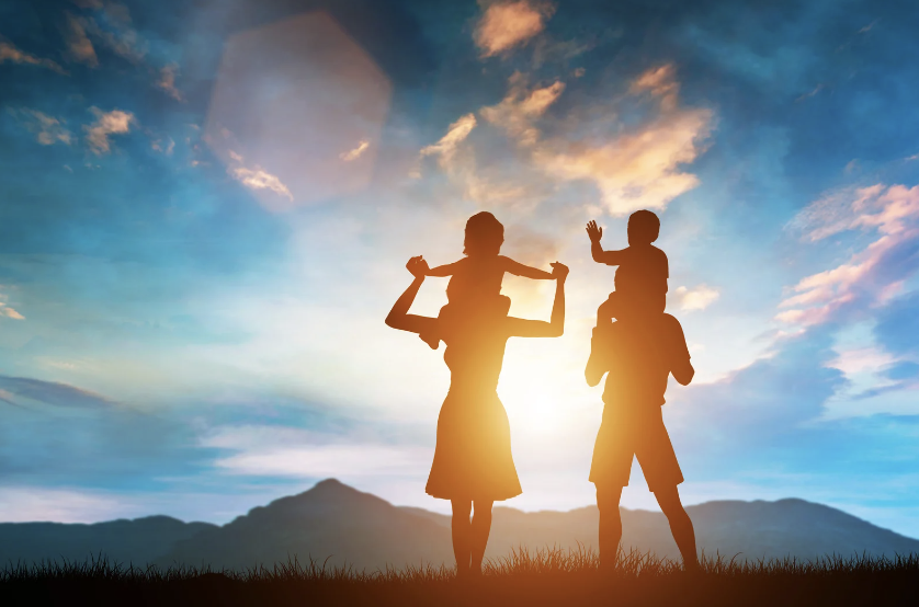 Silhouette of parents with their children on their shoulders in the sun
